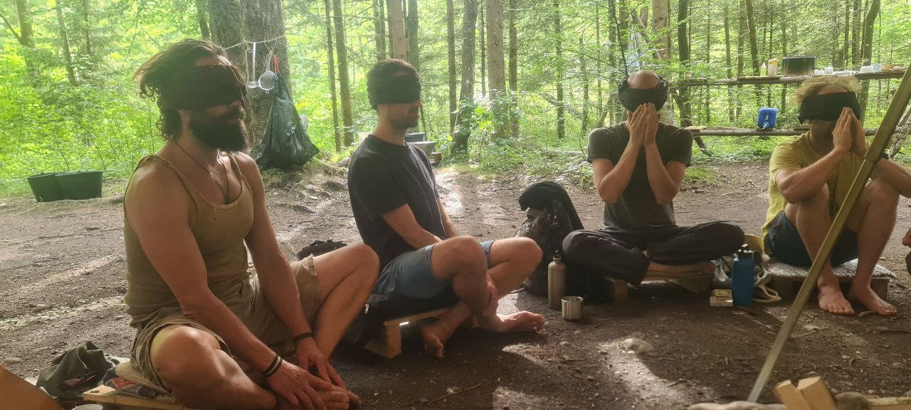 Teilnehmer sitzen während einer Übung mit verbundenen Augen im Kreis.